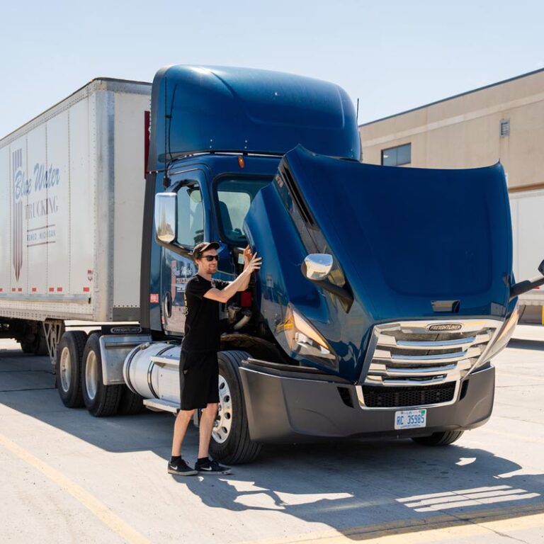 Blue water trucking driver opening hood of truck